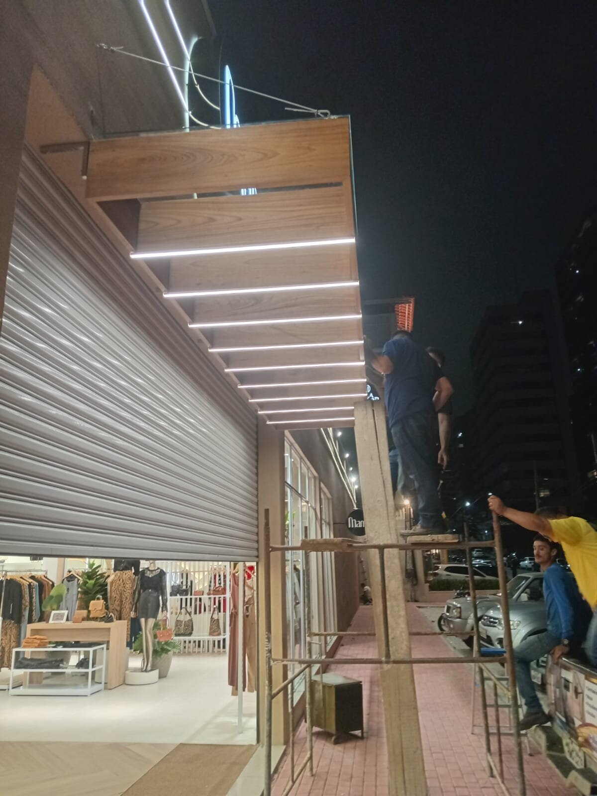 Equipe instalando pergolado em fachada comercial